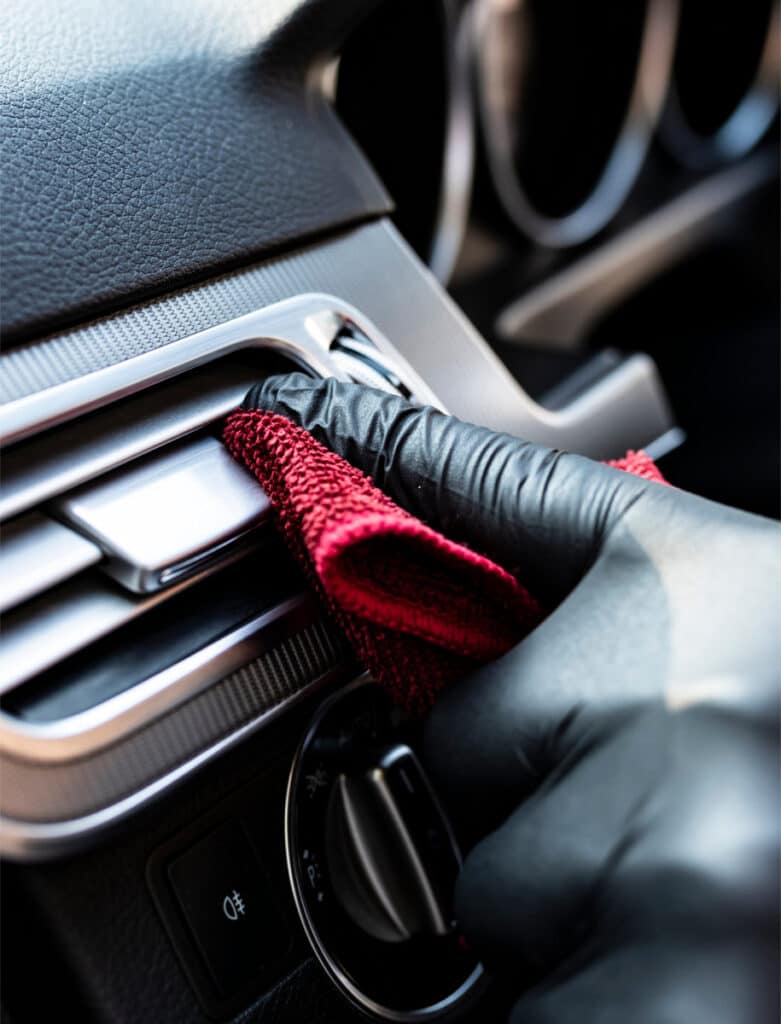 Interior dashboard vent being cleaned with a microfiber