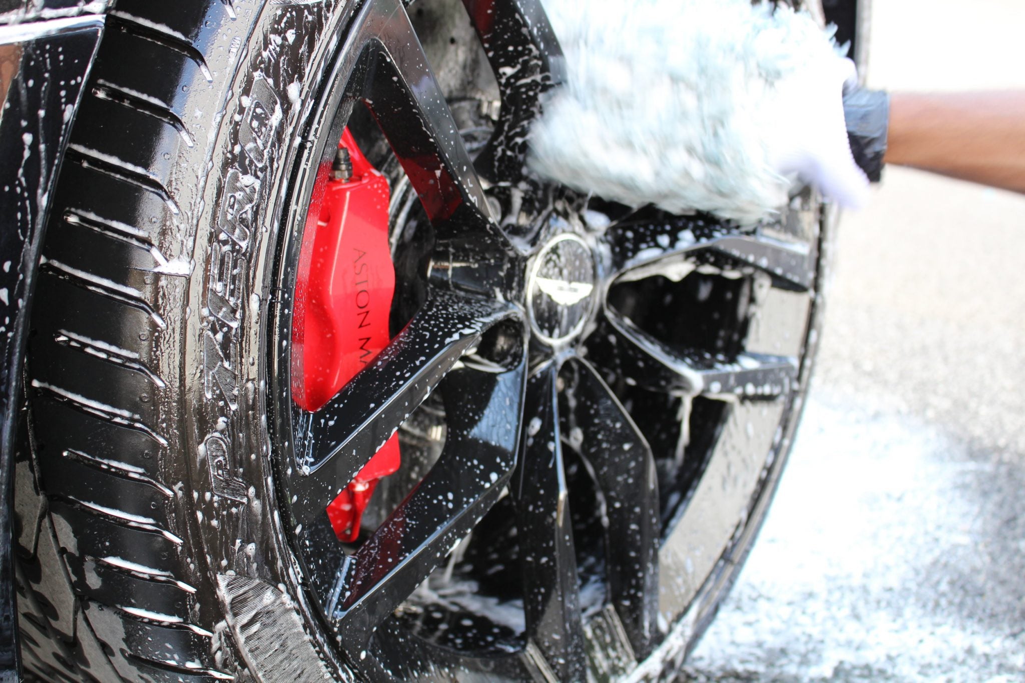 Black wheel with red brake caliper being detailed